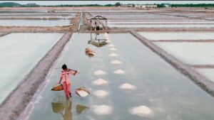 A woman carries baskets of sea salt in the Cambodia drone documentary, 'Of Tears and the Sea' by Jason Rosette of Camerado Media (2022)